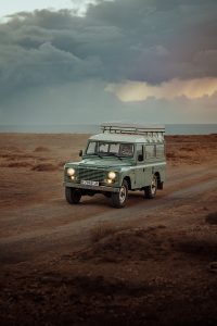 a green vehicle driving down a dirt road