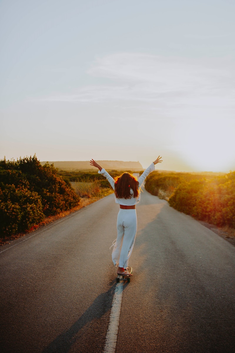 a woman riding a skateboard down a road