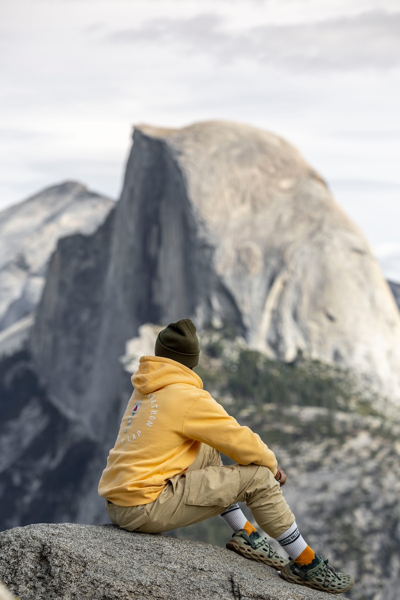 a man sitting on top of a rock next to a mountain